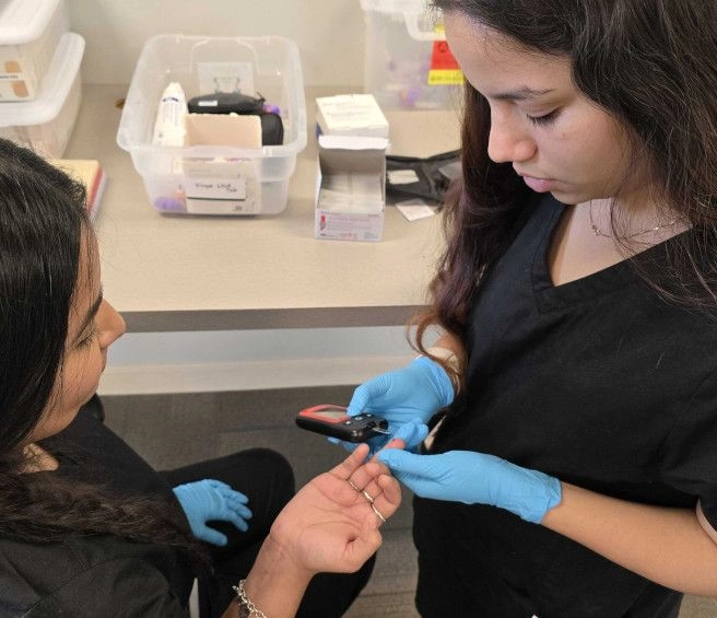 student training to take blood from a finger prick student training to take blood from a finger prick
